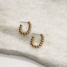 Image shows the Tiffany Gold Beaded Open Hoop Earrings against a white marble background.  Earrings are small open hoops with gold beads.