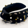 Image shows the Game Day Embellished Headband against a white background. Headband has black fabric and football, pearl,  gold bead, and rhinestone embellishmebnts.