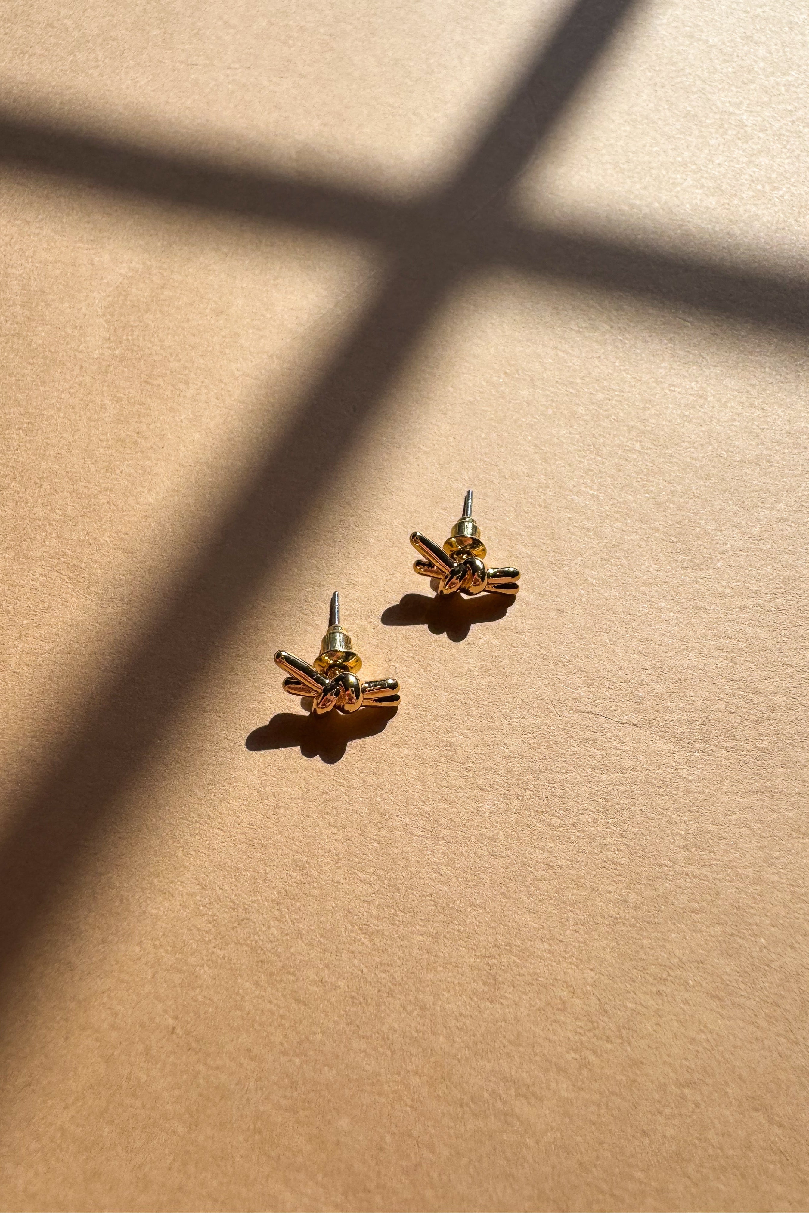 Ivy Gold Knot Stud Earrings - flat lay side view