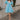Full body view of female model wearing the  Gloria Light Blue Short Sleeve Mini Dress which features aqua blue cotton fabric, aqua blue lining, mini length, ruffle tiered details, a sweetheart neckline with drawstring ties, a smocked back, and short puff sleeves.
