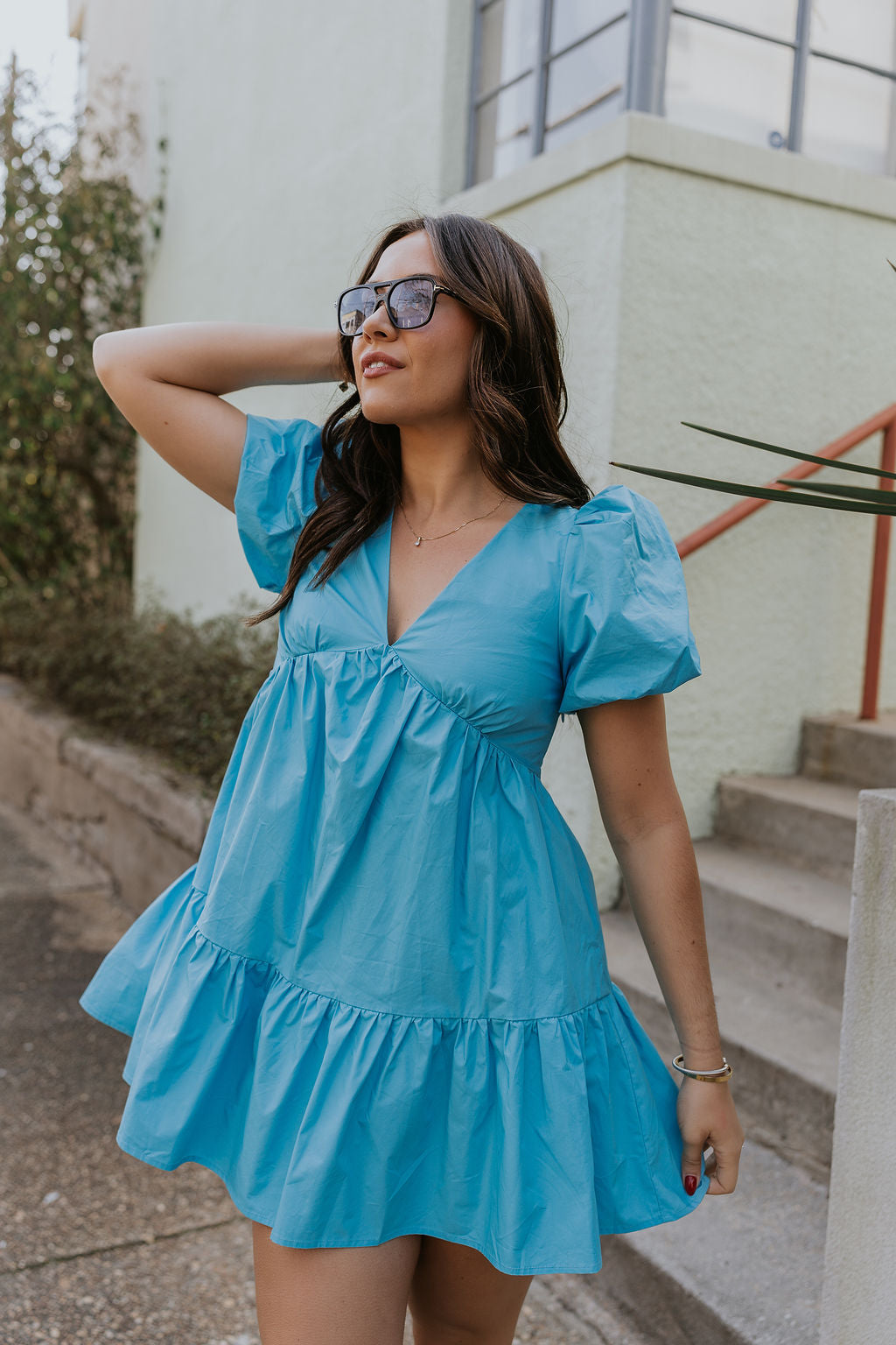 Front view of female model wearing the Stephanie Light Blue Short Puff Sleeve Mini Dress which features light blue light weight fabric, mini length, flared skirt, plunge neckline, short puff sleeves, tie closure in the back and monochrome side zipper with hook closure.