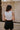 Back view of model wearing the Tiffany Black Shorts which features black fabric with black lining, a front zipper with hook closures, side pockets, faux back pocket details, belt loops, and front pleats.