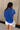 Back view of model wearing the Everly Blue Ribbed Short Sleeve Top that features dark blue and light blue contrast ribbing, a round neckline, and short dolman sleeves with ribbed cuff details.