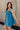 Side view of model wearing the Lucille Dark Turquoise Sleeveless Mini Dress which features dark turquoise fabric, a smocked sweatheart neckline and back, smocked thick straps, and dark turquoise lining.