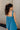 Back view of model wearing the Lucille Dark Turquoise Sleeveless Mini Dress which features dark turquoise fabric, a smocked sweatheart neckline and back, smocked thick straps, and dark turquoise lining.
