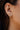 model wearing gold bow stud earrings with clear rhinestones in ear