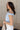 Side view of model wearing the Oakley Light Blue Sleeveless Top which features light blue knit fabic, cropped waist, scooped neckline, thick straps and sleeveless.