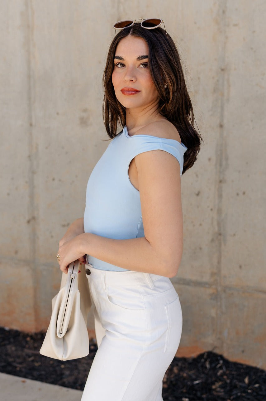 Side view of model wearing the Oakley Light Blue Sleeveless Top which features light blue knit fabic, cropped waist, scooped neckline, thick straps and sleeveless.