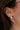 Side view of model wearing pearls with gold and clear rhinestones bows attached in her ear