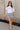 Full body view of model wearing the Sloane Light Denim Wash Skirt which features light wash stretchy denim fabric, a front zipper with a snap closure, large side pockets with snap closures, back pockets, belt loops, and contrast stitching.