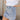 Side view of model wearing the Sloane Light Denim Wash Skirt which features light wash stretchy denim fabric, a front zipper with a snap closure, large side pockets with snap closures, back pockets, belt loops, and contrast stitching.