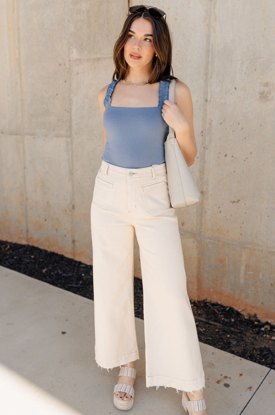 Full body view of model wearing the Ceros: Florence Ecru Wide Leg Jeans which features ecru denim fabric, a front zipper with a button closure, belt loops, a super high-rise waist, two front pockets, two back pockets, and wide cropped legs with distressed hems.