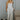 Full body view of model wearing the Celeste Ivory V-Wire Sleeveless Jumpsuit which features ivory knit fabric, full-length ivory lining, a structured notched neckline, thick straps, side pockets, and wide legs.