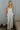 Full body view of model wearing the Celeste Ivory V-Wire Sleeveless Jumpsuit which features ivory knit fabric, full-length ivory lining, a structured notched neckline, thick straps, side pockets, and wide legs.