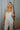 Front view of model wearing the Celeste Ivory V-Wire Sleeveless Jumpsuit which features ivory knit fabric, full-length ivory lining, a structured notched neckline, thick straps, side pockets, and wide legs.