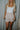 Front view of model wearing the Juliette Cream Fray Shorts cream textured knit fabric, cream lining, fray hem details, two front pockets and front zipper with pearl button closure.
