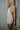 Side view of model wearing the Juliette Cream Fray Shorts cream textured knit fabric, cream lining, fray hem details, two front pockets and front zipper with pearl button closure.