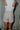 Back view of model wearing the Juliette Cream Fray Shorts cream textured knit fabric, cream lining, fray hem details, two front pockets and front zipper with pearl button closure