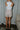 Full body back view of model wearing the Juliette Cream Fray Shorts cream textured knit fabric, cream lining, fray hem details, two front pockets and front zipper with pearl button closure.