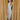 Full body view of model wearing the Elisya Cream Ruched Midi Dress which features cream sheen knit fabric, midi length, cream lining, slit on the side, ruched side details, high neckline and sleeveless.