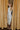 Full body view of model wearing the Elisya Cream Ruched Midi Dress which features cream sheen knit fabric, midi length, cream lining, slit on the side, ruched side details, high neckline and sleeveless.