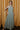 Full body view of model wearing the Cleo Green & White Halter Twist Midi Dress which features white and green lightweight fabric, geometric design, maxi length, halter twist neckline, sleeveless and open back with monochrome back zipper with hook closure.
