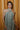 Front view of model wearing the Cleo Green & White Halter Twist Midi Dress which features white and green lightweight fabric, geometric design, maxi length, halter twist neckline, sleeveless and open back with monochrome back zipper with hook closure.