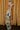Full body side view of model wearing the Alexandria Multi Abstract Halter Maxi Dress which features yellow, white, orange, green, and pink abstract print, cream full length lining, adjustable straps, a halter neckline with a tie, a low back, and a maxi length hemline.