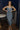 Full body view of model wearing the Lucia Acid Indigo Denim Midi Dress which features acid medium wash denim fabric, midi length, silver button-up front closure, slit in the back, two back pockets, belt loops, sweetheart neckline, straps and open back.