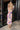 Full body back view of model wearing the Isla Multi Swirl Midi Dress which features purple, fuchsia, peach, yellow, green, light pink and white knit fabric, wattercolor swirl print, peach lining, mid length, v-neckline, thick straps and sleeveless.
