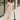 Full body view of model wearing the Daphne Oatmeal Button-Up Midi Dress which features beige fabric, a button-up front with pearlescent buttons, a collared neckline, short sleeves with cuffs and button tabs, and a rounded midi hemline.