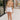 The girl model is wearing white denim shorts with a frayed hem.  This is a front shot of her wearing the shorts with a tan tank top. 