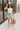 Full body front view of female brunette model wearing the light wash color of the Hayden Frayed Hem Denim Shorts, paired with a white tank top.