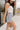 Side view of female brunette model wearing the light wash color of the Hayden Frayed Hem Denim Shorts, paired with a white tank top.