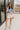 Full body front view of female brunette model wearing the Mckenzie Off White Denim Shorts that feature off white denim, contrast stitching, pockets, and a high rise. Styled with blue and white floral top.
