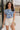Front view of model wearing the Carmen Blue & Cream Floral Top which features blue and cream knit fabric, floral pattern, round neckline, ruffle short sleeves and keyhole back with button closure.