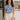 Front view of female brunette model wearing the Mckenzie Off White Denim Shorts that feature off white denim, contrast stitching, pockets, and a high rise. Styled with blue and white floral top.