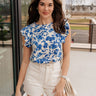 Front view of female brunette model wearing the Mckenzie Off White Denim Shorts that feature off white denim, contrast stitching, pockets, and a high rise. Styled with blue and white floral top.
