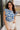 Front view of model wearing the Carmen Blue & Cream Floral Top which features blue and cream knit fabric, floral pattern, round neckline, ruffle short sleeves and keyhole back with button closure.