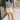 Full body view of model wearing the Carmen Blue & Cream Floral Top which features blue and cream knit fabric, floral pattern, round neckline, ruffle short sleeves and keyhole back with button closure.