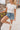 Front view of female blonde model wearing the medium wash color of the Hayden Frayed Hem Denim Shorts, paired with a white cropped t-shirt.
