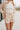 front view of model wearing the Cassidy Beige Gauze Shorts that feature beige gauze fabric, an elastic drawstring waist, side pockets, and frayed hem details.