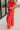 Side view of model wearing the Vada Red Wide Leg Pants that feature red woven fabric, side pockets, an elastic waistband, and flowy wide legs.