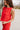 Side view of model wearing the Vada Red Tank Top that features red woven fabric with raw frayed hems, a round neckline, a sleeveless body, small side slits, and a keyhole back with a button closure.