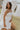 Side view of female model wearing the Abigail Strapless Flare Mini Dress in white which features features Mini Length, Lining, Two Side Pockets, Strapless and Monochrome Back Zipper with Hook Closure.