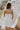 Back view of female model wearing the Abigail Strapless Flare Mini Dress in white which features features Mini Length, Lining, Two Side Pockets, Strapless and Monochrome Back Zipper with Hook Closure.