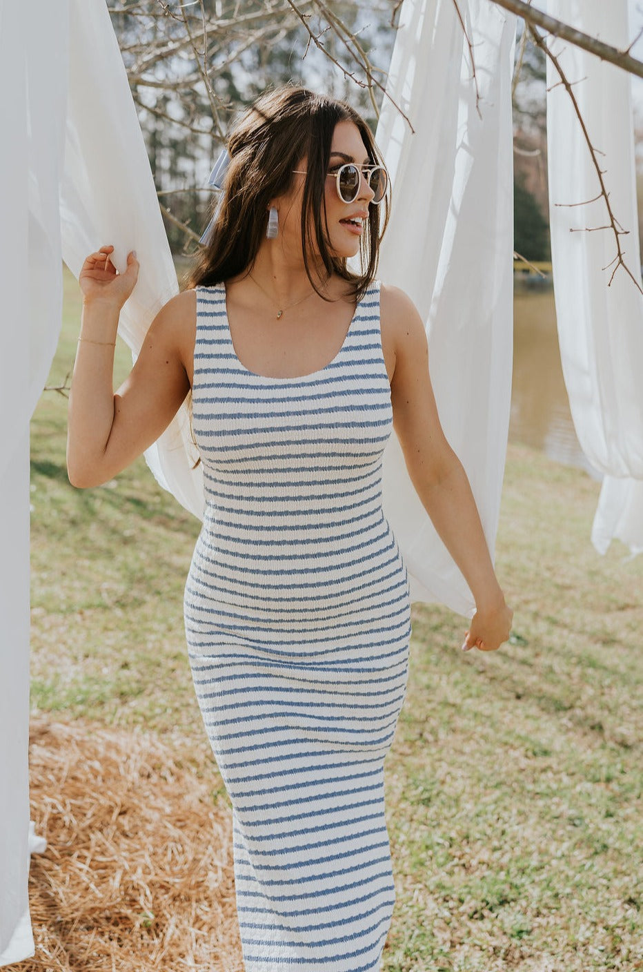 Front view of female model wearing the Casey Cream & Blue Striped Midi Dress that has cream and blue horizontal stripes, bodycon fit, thick straps, a side slit, and round neck.