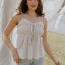 Front view of female model wearing the Billie White & Taupe Striped Tank that has thin vertical stripes, front tie details, ruffle trim, and spaghetti straps