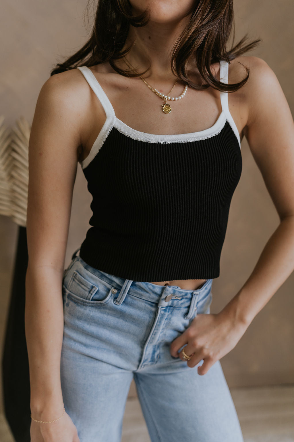 Close up view of female model wearing the Veronica Black & White Ribbed Tank which features Black Ribbed Fabric, Square Neckline, White Trim Details and Sleeveless.