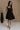 Full body view of female model wearing the Abigail Strapless Flare Mini Dress in black which features features Mini Length, Lining, Two Side Pockets, Strapless and Monochrome Back Zipper with Hook Closure.